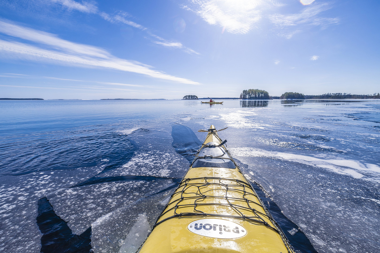 Keltainen kajakki lipuu järvellä. Järven pinnalla on hieman riitettä.