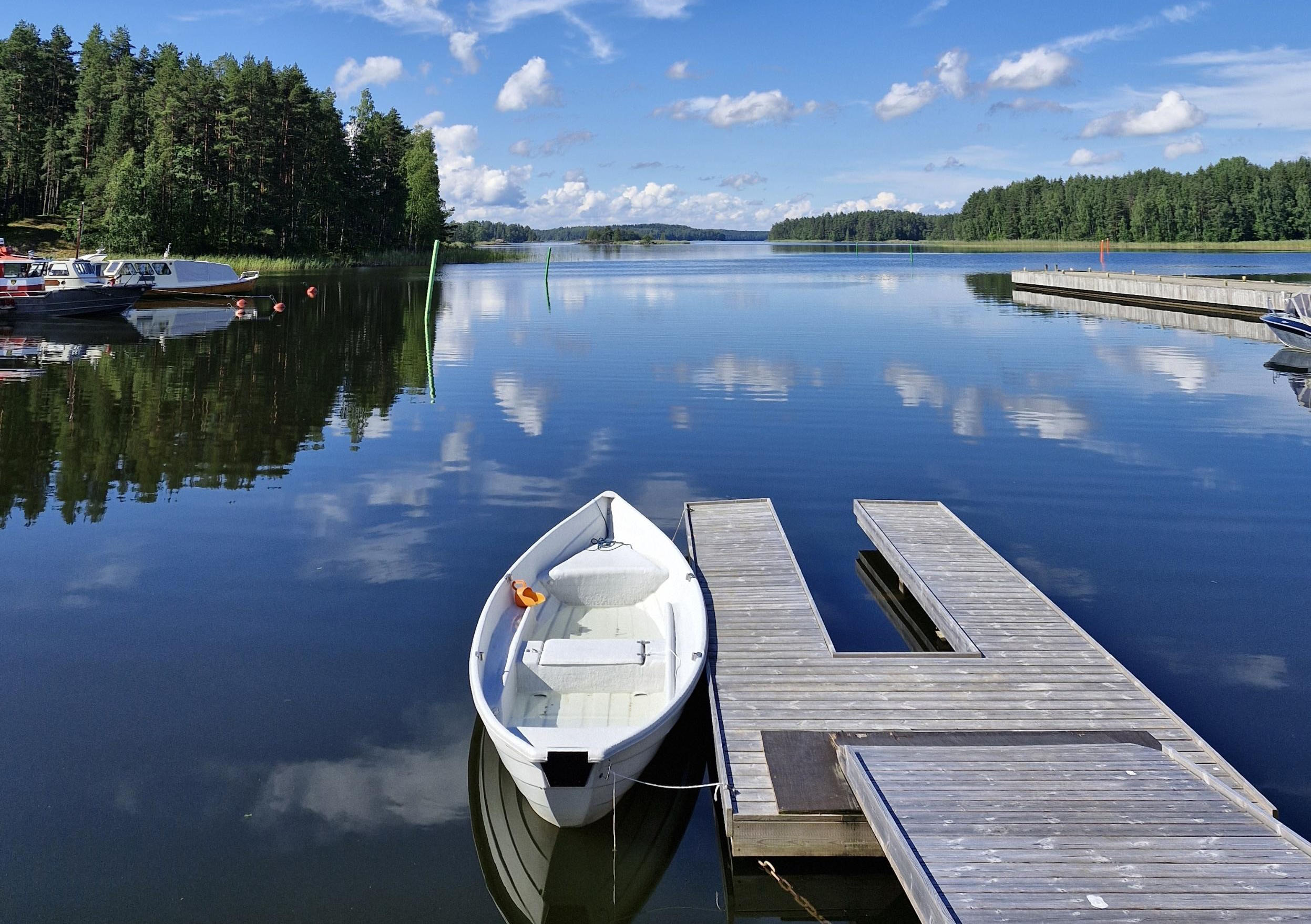 Valkoinen soutuvene laiturin vieressä.