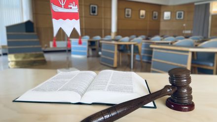 Valtuustosalin pöydällä avoin kirja, puinen nuija ja Taipalsaaren pöytävaakuna.