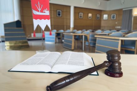 Valtuustosalin pöydällä on nuija ja avoin lakikirja sekä kunnan pöytäviiri.