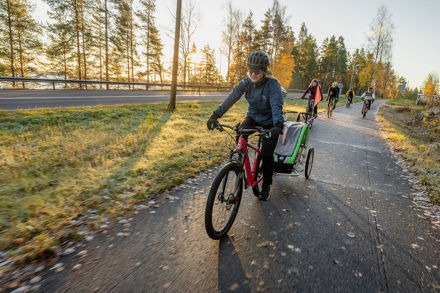 Pyöräilijöitä ajamassa pyörätiellä syksyisessä maisemassa.