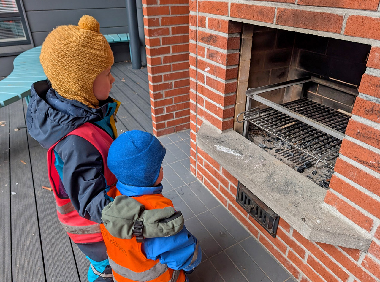 Kaksi lasta seisoo takan edessä.